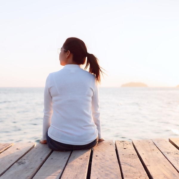 A person sitting on a dock looking at the ocean