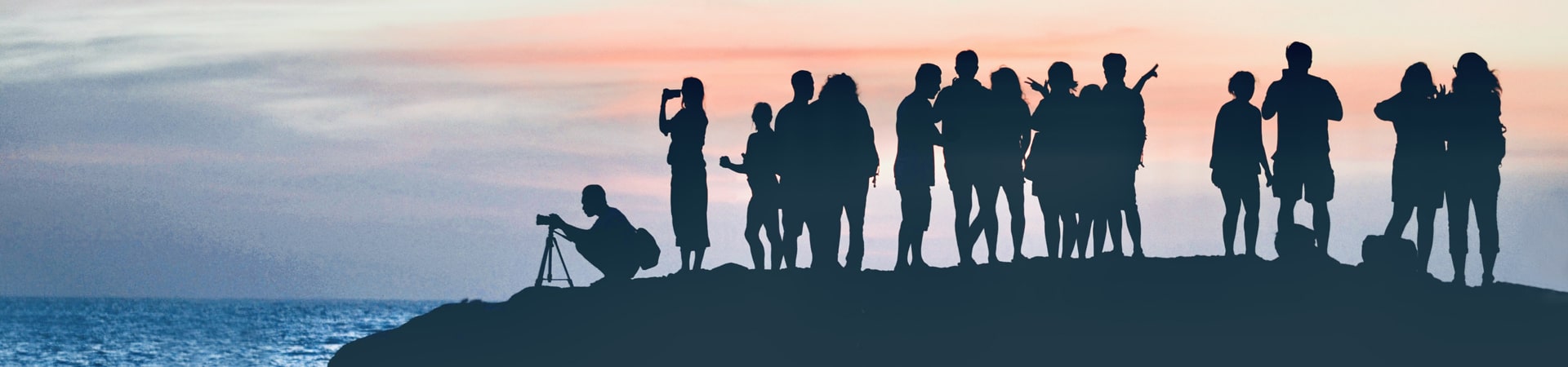 Silhouettes of a group of people at a shore